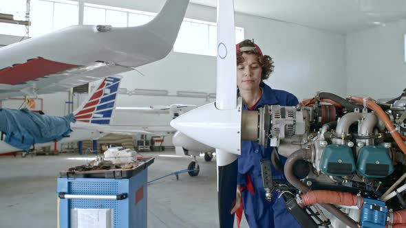 Female Technician Inspecting Aircraft Engine
