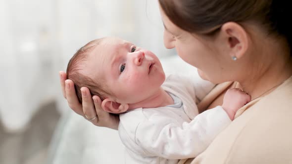 Above View on Young Caring Mother Hugging and Cuddlingher Newborn Baby Son in Bedroom with Big