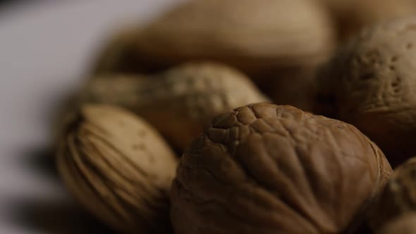 Cinematic, rotating shot of a variety of nuts on a white surface