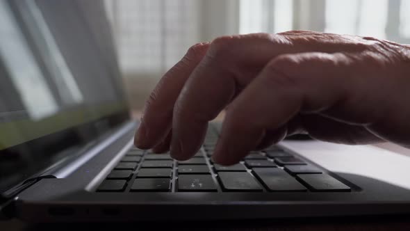 Female Wrinkled Fingers Touch Black Keys of Laptop Keyboard