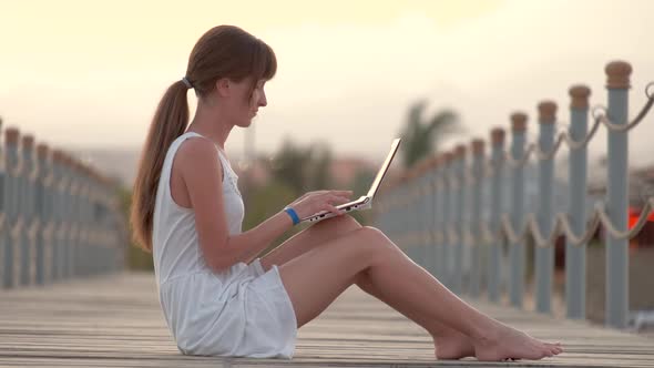 Young Female Office Worker Working on Laptop Computer Outdoors on Warm Summer Evening