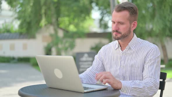 Thumbs Up By Middle Aged Man with Laptop in Outdoor Cafe