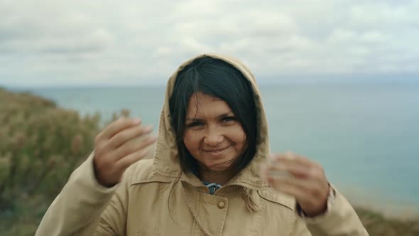 Portrait of a Girl in a Hood Looking at the Camera on the Background of the Sea