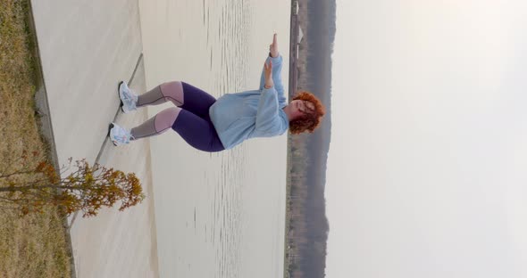 curly girl with red hair doing squats raising her hands in front of her