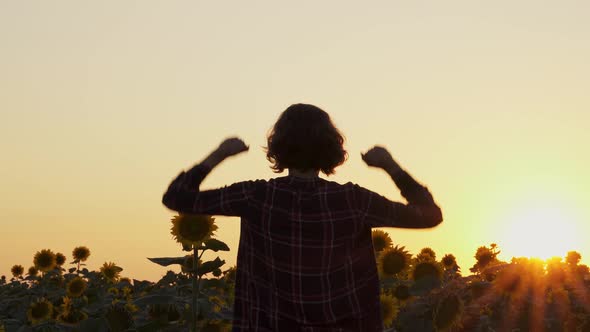 Farmer In Field Rejoices In Success. Woman Hands In Air. Feeling Motivated, Strong, Courageous