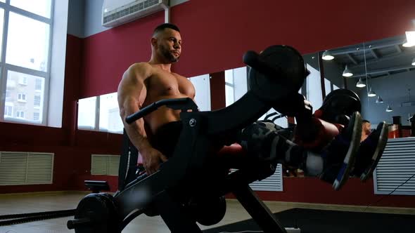 Bodybuilder Training Legs. Man Doing Exercise with Weightlifting Machine in Fitness Center. Muscle