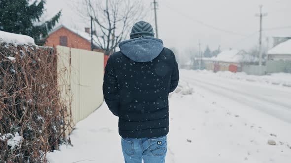 Back of a Walking Man in Snowy Weather