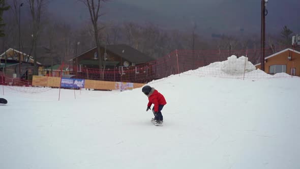 Young Man Snowboard Instructor Tiches Little Boy How To Ride a Snowboard. Winter Activities Concept