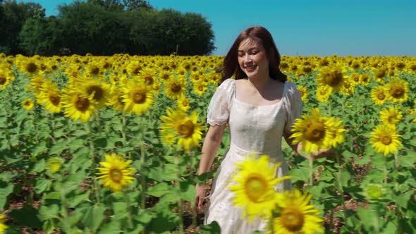 cheerful woman walking and enjoying with sunflower field