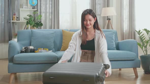 Asian Woman Preparing For Travel Adventure, Packing Clothes And Close Suitcase