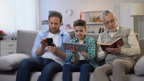 Middle-Aged Male and Preteen Boy Scrolling Gadgets, Aging Man Reading Paper Book