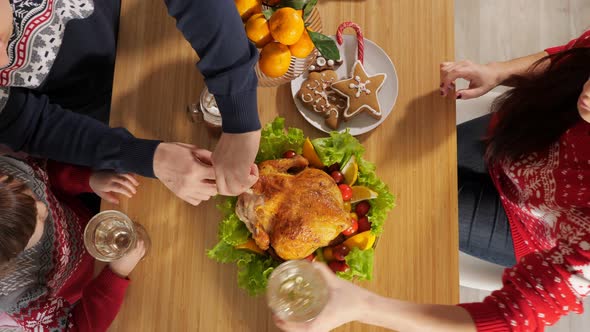 Husband Cuts Chicken Sitting at Dinner Table on New Year Eve