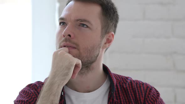 Pensive Young Man Thinking and Working on Laptop