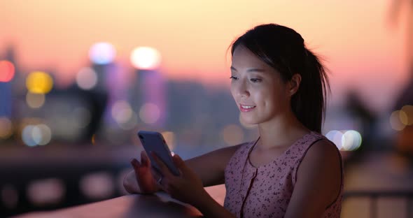 Woman use of mobile phone at sunset time