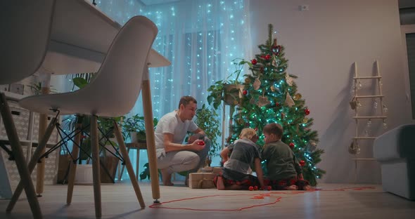 Samya Father and Two Sons Together Decorate the Christmas Tree for the New Year and Christmas