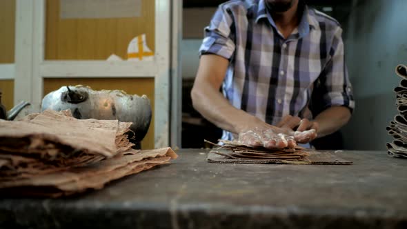 Worker applying glue on small pieces of leather garment in the factory.
