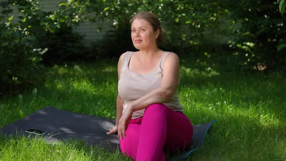 Positive Plussize Woman Sitting on Green Grass in Garden Enjoying Summer Day Outdoors