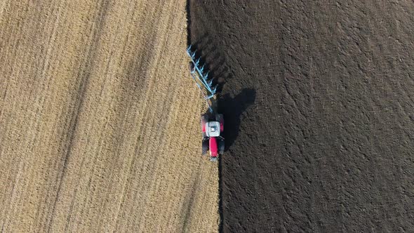 Tractor pulls a plow across a farm field. preparation of the field before sowing. Drone view.