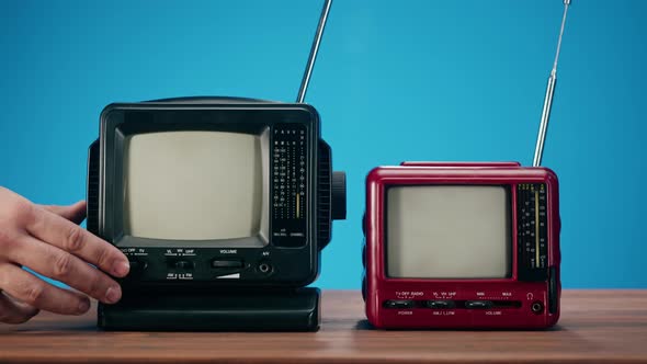 Turning on Small Old Televisions with Grey Interference Screen on Blue Background