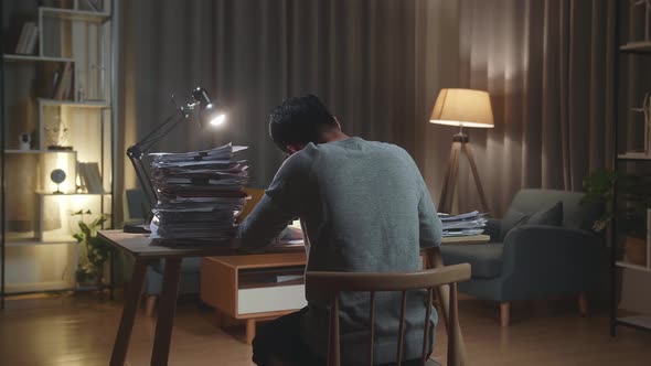 Back View Of Asian Man Working With Documents At The Home