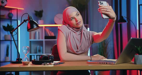 Arabian Woman Sitting at Her Workplace in Home Office in the Evening and Making Selfie