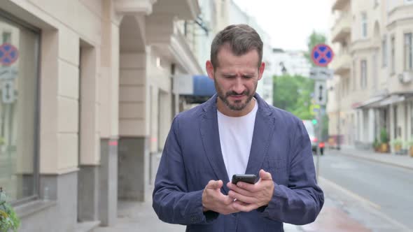 Man Having Loss on Phone While Walking Down the Street