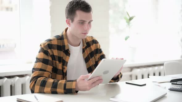 Casual Young Man Scrolling Internet on Tablet