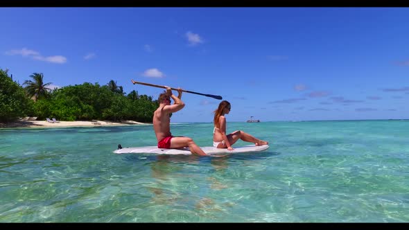 Young couple tanning on perfect coast beach break by aqua blue sea and white sandy background of the