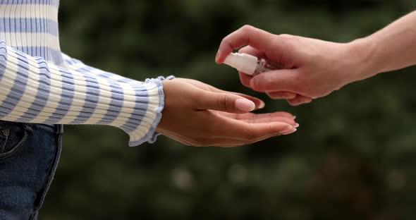 Man disinfecting hands her girlfriend.