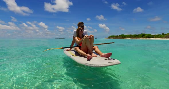 Young lady and man on romantic honeymoon have fun on beach on sunny white sandy background 