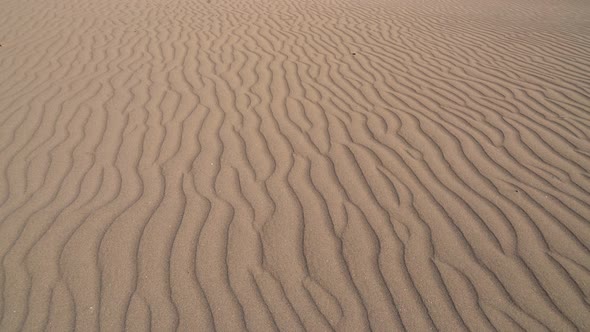 Parallel Sand Pattern Lines on Dune Surface in Desert