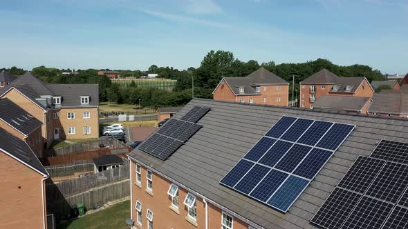 Aerial drone footage of a British house with solar panels on the roof, on a sunny summers day.