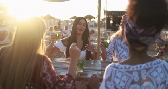 Happy multiracial girls having fun drinking mojitos at beach party outdoor