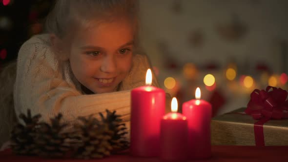 Cute Blond Girl Looking at Burning Candles on Christmas Eve, Waiting for Magic