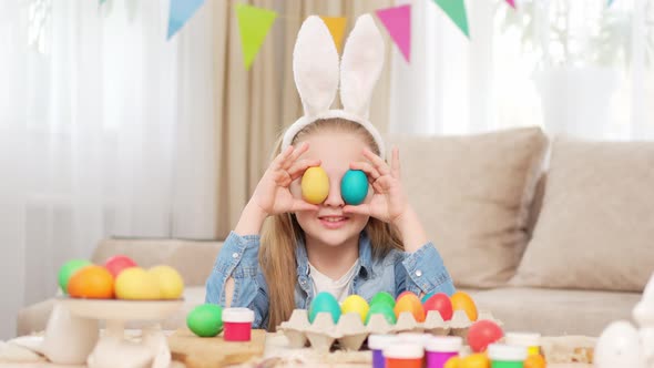 Happy Teen Girl with Rabbit Ears Celebrates Easter and Plays with Painted Eggs