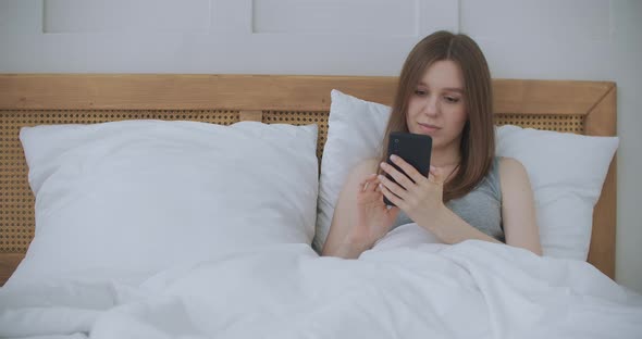 Face Close-up on Woman Typing a Message on a Mobile Phone Using 2 Hands