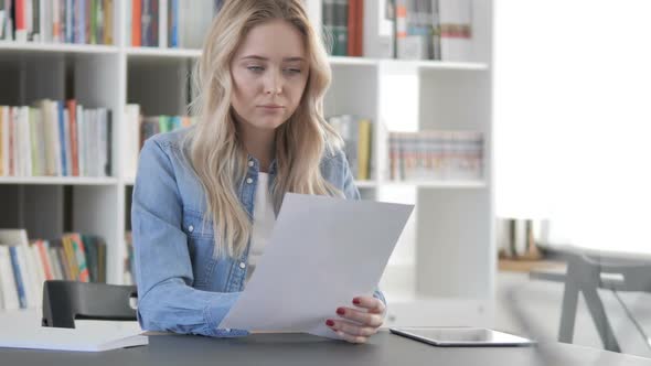 Young Woman Reading Contract Documents in Office