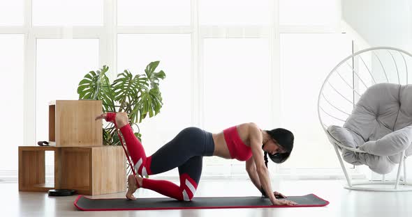 Athletic muscular girl sportswoman does exercise for buttocks with loop band.