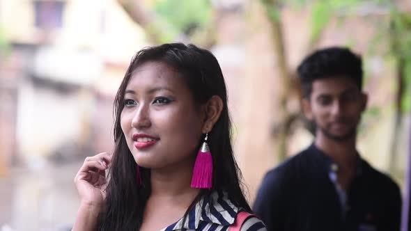 Girl feeling shy in foreground, boy standing in background looking at her, romantic cute Asian coupl