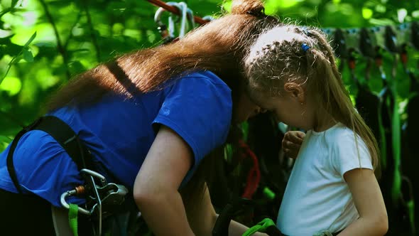 Rope Adventure - a Woman Instructor Puts on the Insurance Pendants on the Waist of a Little Girl