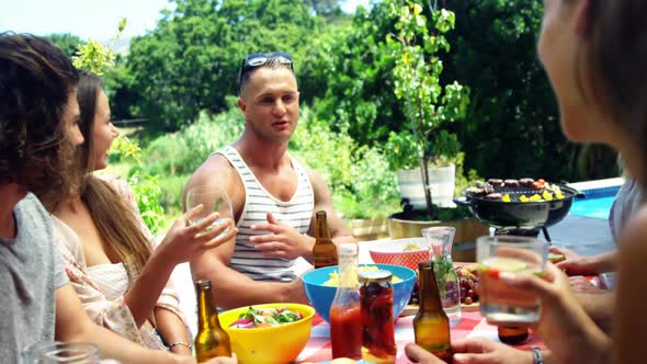 Group of friends interacting with each other while having drink at outdoors barbecue party