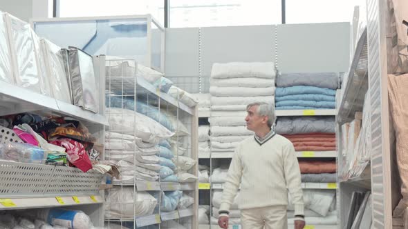 Elderly Man Walking in Home Department Store, Shopping for Bedding