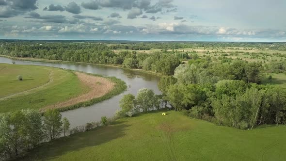 Flight Over Green Meadow and River in Spring