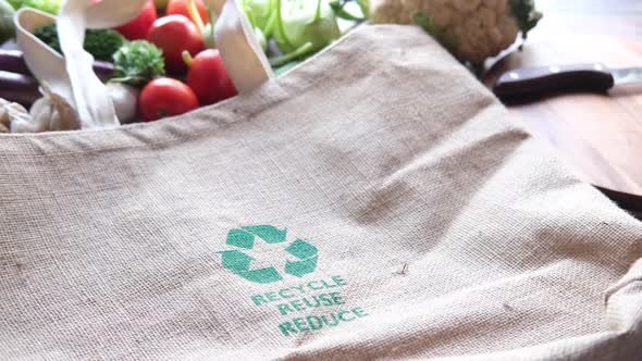 Reusable Shopping Bag with Recycled Arrows Sign and Vegetables on Table
