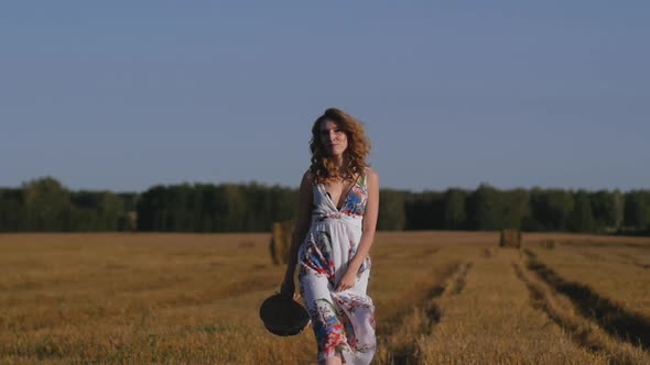 Young Redhead Woman with Wicker Basket Walks in the Field Enjoying Nature