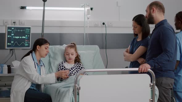 Pediatrician Woman Doctor Putting Medical Oximeter on Little Child Patient Finger