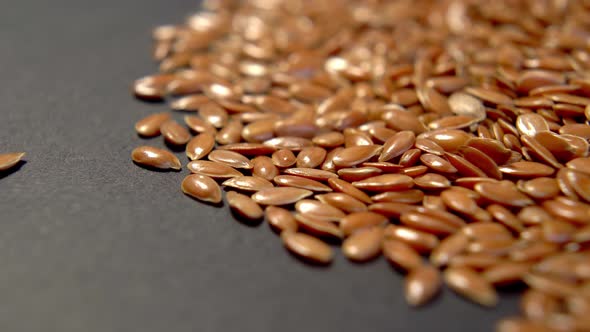 Flax seed heap on dark packaging paper. Brown linseeds. Macro