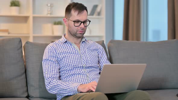 Serious Young Man Working on Laptop at Home 