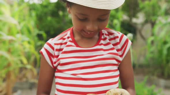 African American girl showing potatoes at the camera