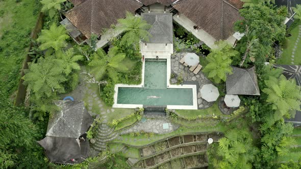 Man swims in a pool, bali villa, travel drone